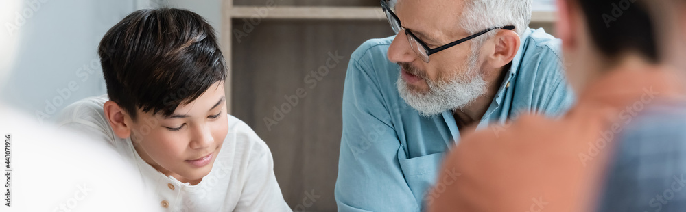 Mature teacher looking at asian schoolboy, banner Mature teacher looking at asian schoolboy, banner