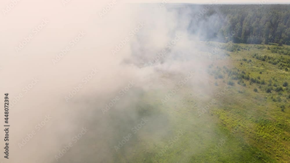 Puffs of smoke and fire spread across a large field. Aerial view, fire in the field, dry grass is burning. Forest fires in the countryside in summer. Climate change and ecology concept. UHD 4K. Puffs of smoke and fire spread across a large field. Aerial view, fire in the field, dry grass is burning. Forest fires in the countryside in summer. Climate change and ecology concept. UHD 4K.