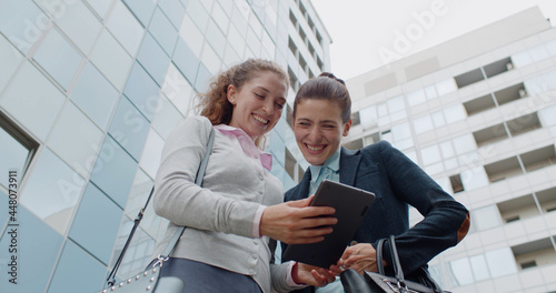 Low angle view of female colleagues using digital tablet outdoors photo