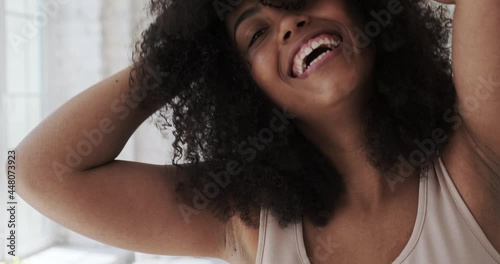 A happy, cheerful young mixed-race woman dancing alone in her boho-style home while listening to music tracks and songs. A student's after-work break and search for inspiration and creativity. photo