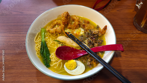 photo of seafood ramen in a big bowl with spoon and chopsticks