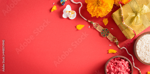 Fototapet Raksha Bandhan, Indian festival with beautiful Rakhi and  Rice Grains on red background