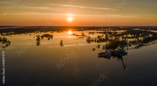 Flooded trees during a period of high water at sunset. Trees in water at dusk. Landscape with spring flooding of Pripyat River near Turov  Belarus. Nature and travel concept.