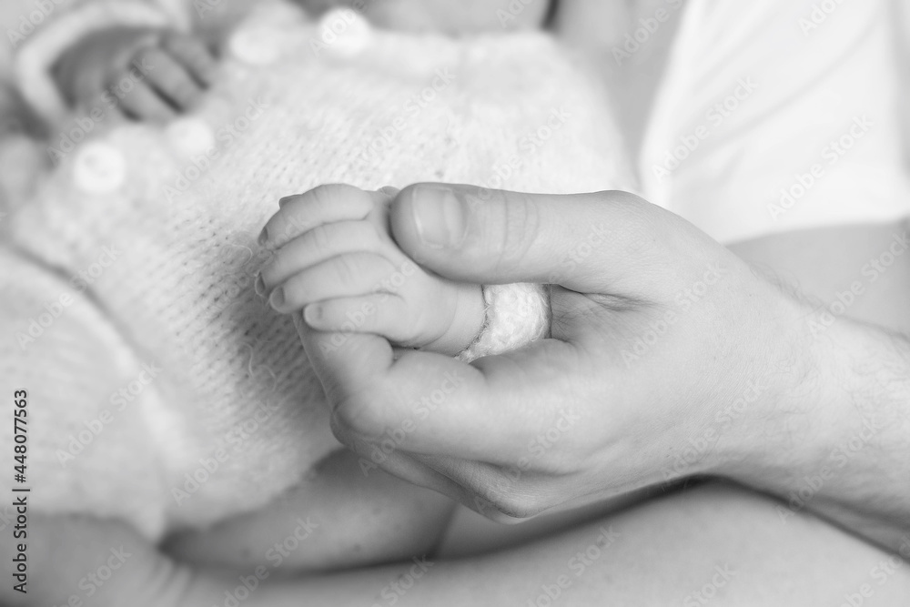 father holds a newborn baby by the hand. black and white photo father holds a newborn baby by the hand. black and white photo