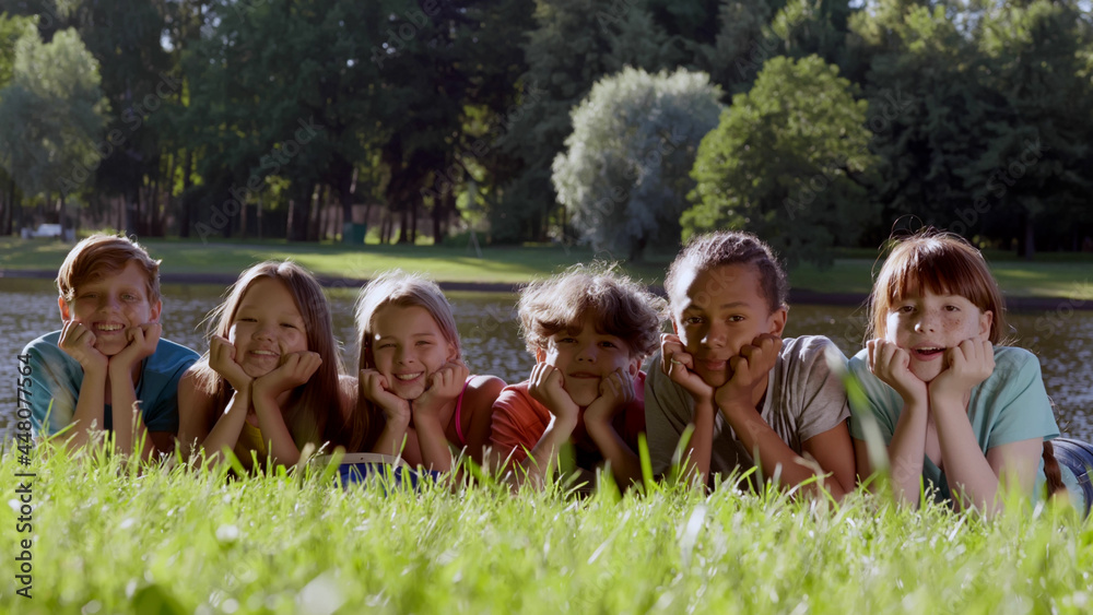 Portrait of diverse children lying on grass in park and smiling at camera Portrait of diverse children lying on grass in park and smiling at camera