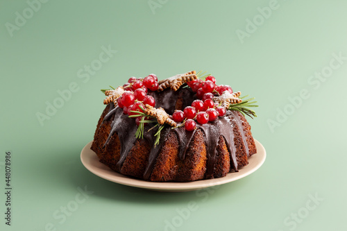 Tasty Christmas and New Year pie with chocolate and berries at solid green background.