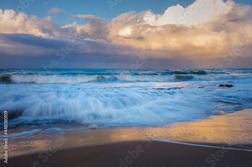Rocks on the beach during sunset. Waves and sea foam in the form of a cloud. © Horacio Selva
