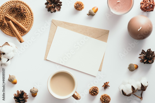 Autumn feminine desk table with romantic letter, coffee cup, candles, pine cones, cotton, cinnamon sticks on white background. Flat lay, top view.