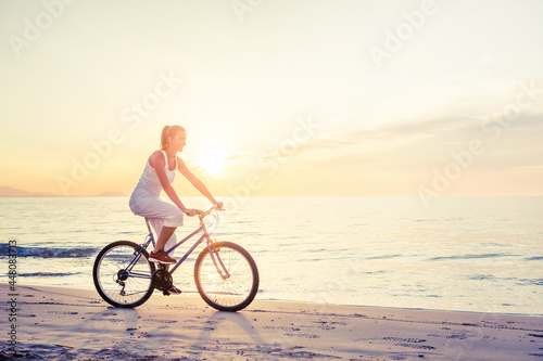 Beautiful woman rides a bicycle by the sea