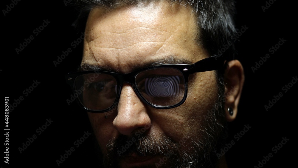 Man hypnotized by a spiral hypnotic effect looking at the computer screen. Reflection on the glasses. Man hypnotized by a spiral hypnotic effect looking at the computer screen. Reflection on the glasses.