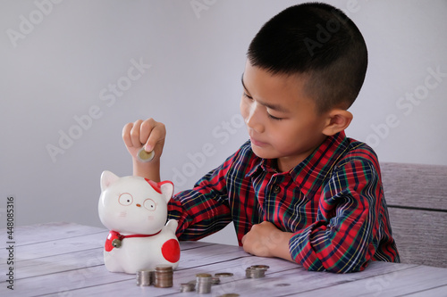 Boy coining Happily put in a piggy Ceramic cat piggy bank It is a way for children to know how to save and save money. for the future of children concept of saving money 