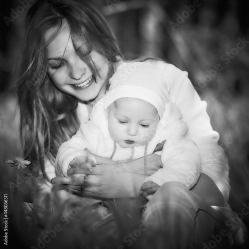Happy young mother playing and having fun with her little baby son on a sunrise warm spring or summer day. Beautiful sunlight in the park. Happy family concept. Black and White