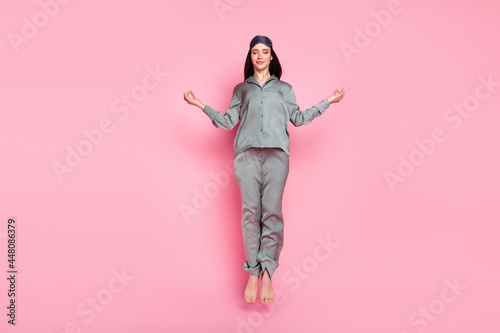 Photo of adorable shiny young lady sleepwear jumping high practicing yoga smiling isolated pastel pink color background