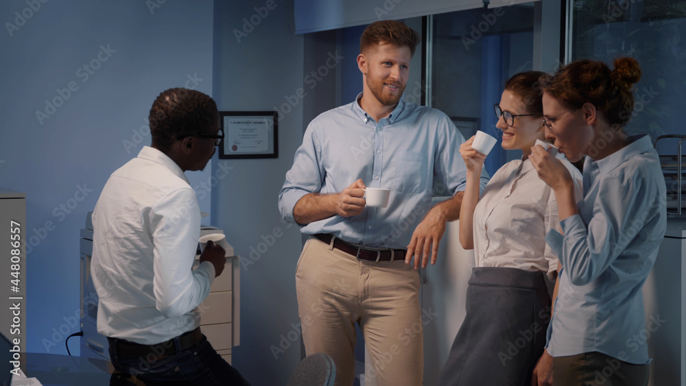 Naklejka premium Young multiethnic coworkers having fun conversation during coffee break in modern office