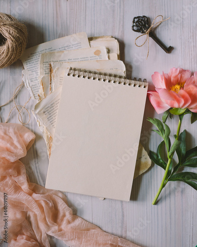 paper notebook on vintage papers, toned photo, pink peony, vintage key, top view, selective focus, copy space for text