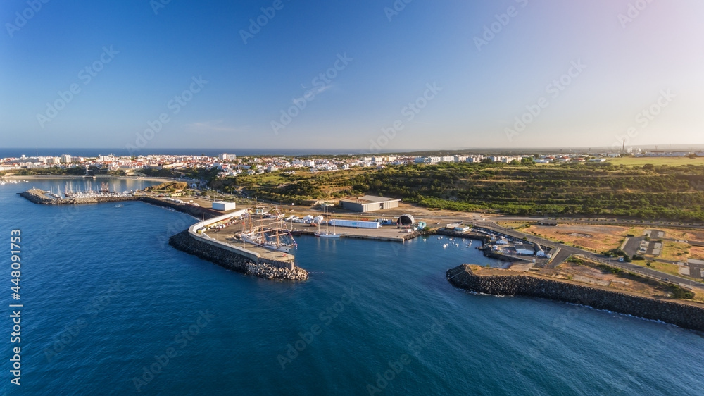 Aerial. The maritime dock in the Portuguese city of Sines and the sailboat is moored for tourist excursions. Blue ocean. Sanny day