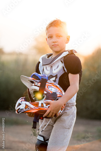 Child rider on motorcycle. Small biker dressed in a protective suit and helmet. The kid is engaged in motocross