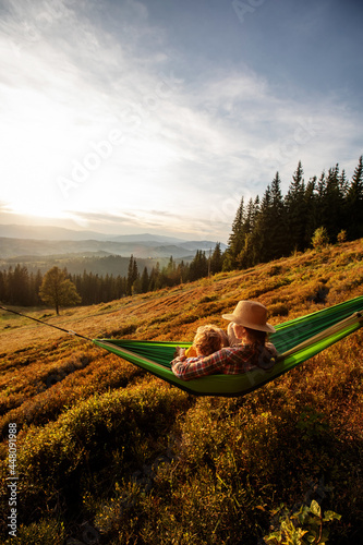 Boy tourist resting in a hammock in the mountains at sunset