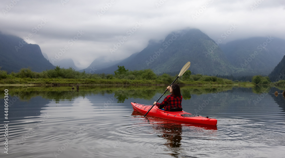 Adventure Caucasian Adult Woman Kayaking in Red Kayak surrounded by Canadian Mountain Landscape. Taken in Widgeon Valley, Pitt Meadows, Vancouver, British Columbia, Canada.