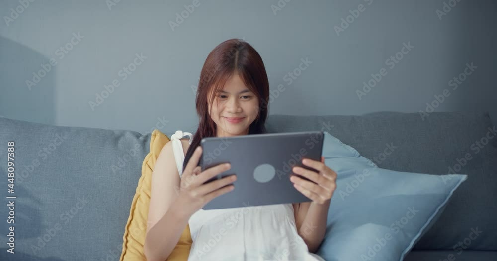 Happy youth Asia girl teenage with relax use digital tablet watch online movie enjoy korean series in living room at house. Isolate activity lifestyle, Social distance coronavirus pandemic concept. Happy youth Asia girl teenage with relax use digital tablet watch online movie enjoy korean series in living room at house. Isolate activity lifestyle, Social distance coronavirus pandemic concept.
