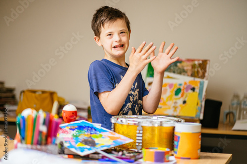 Young Caucasian Boy with Down Syndrome Concentrating On Her Hand Clapping Game in Home or Art Class for special needs children.