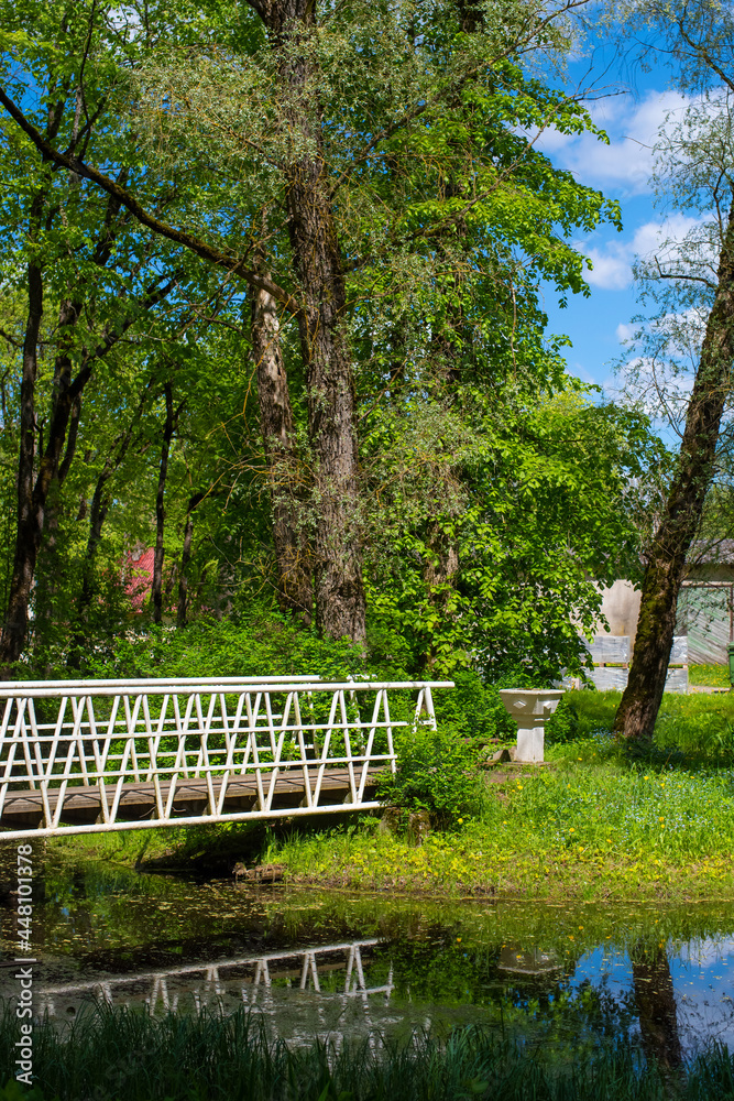 A white wooden bridge in the Poltsamaa city park on a sunny summer day.
