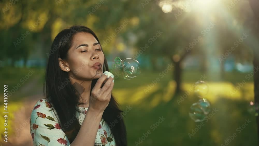 Asian woman blowing soap bubbles at the sunset