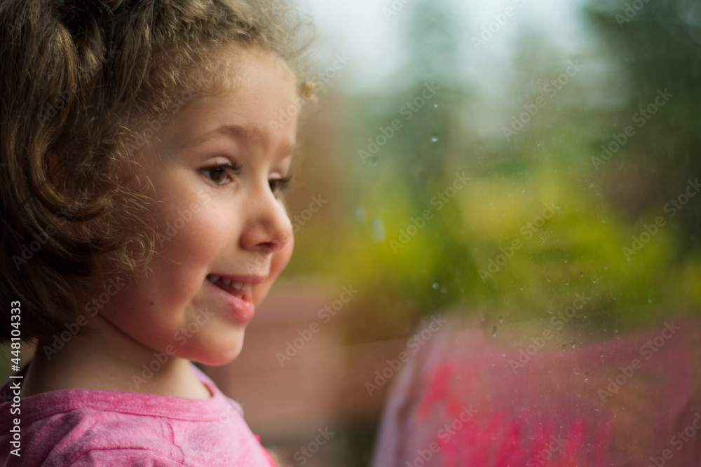 little girl looking out the window of her house. Selective Focus girl. little girl looking out the window of her house. Selective Focus girl.