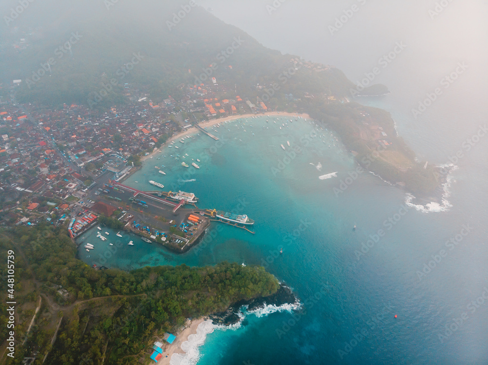Tropical beach and Balinese town and ferry in port and ocean. Aerial view