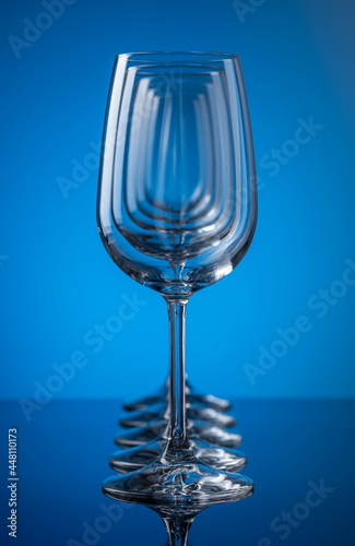 Five wine glasses in row concentric on blue background