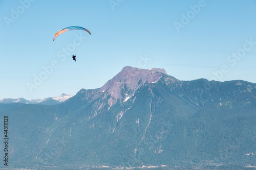 Adventure Composite Image of Paraglider Flying up high in the Rocky Mountains. Sunny Blue Sky. Aerial Background from Fraser Valley, British Columbia, Canada. Extreme Sport Concept