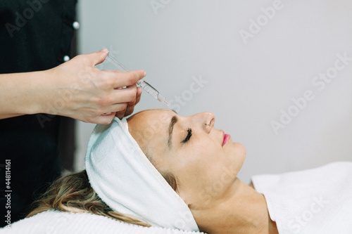 High angle view of woman lying on treatment bed in a beauty salon, receiving facial treatment.