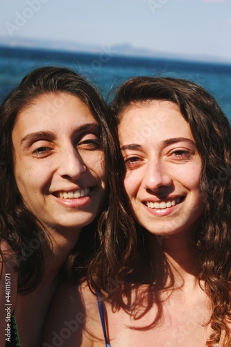 Happy smiling family portrait of siblings / sisters at the beach with sea background © Alp Peker