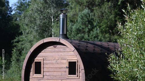 Wooden brown sauna with visible heat and smoke going out of the chimney in green forest background