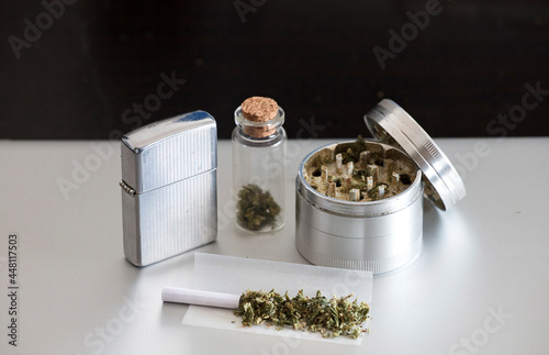 lighter with marijuana joint, transparent container, gray and black background