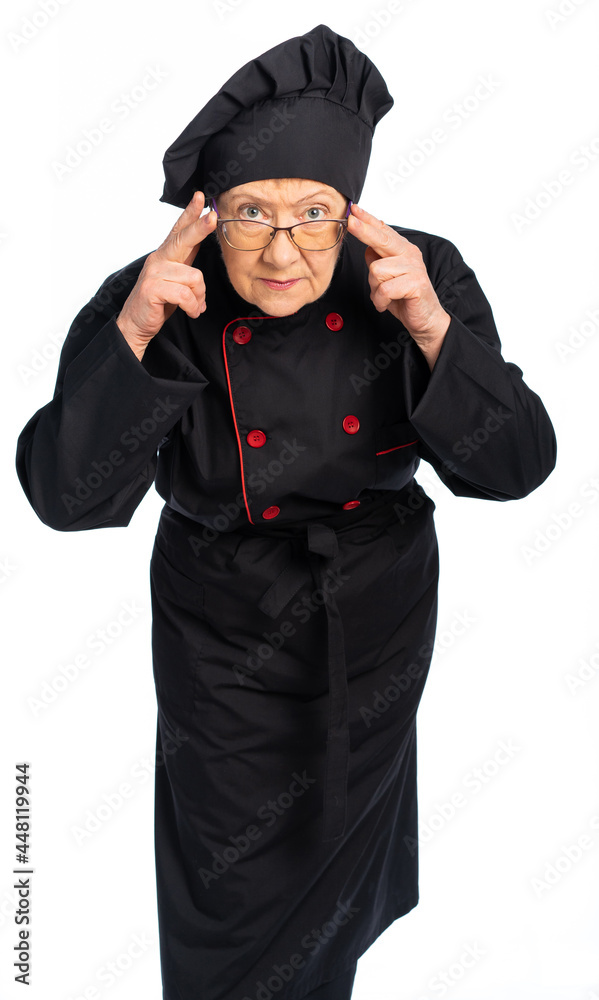 woman chef in black uniform. apron, shirt, hat. an elderly woman leaned forward and looked at the camera over the top of her glasses. examines us carefully. isolated, white background woman chef in black uniform. apron, shirt, hat. an elderly woman leaned forward and looked at the camera over the top of her glasses. examines us carefully. isolated, white background