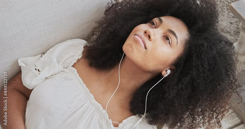 Young black lady relaxing on a comfy sofa, listening to live ambient electronica through smartphone app, peaceful without worry, eyes closed, meditation at home idea.