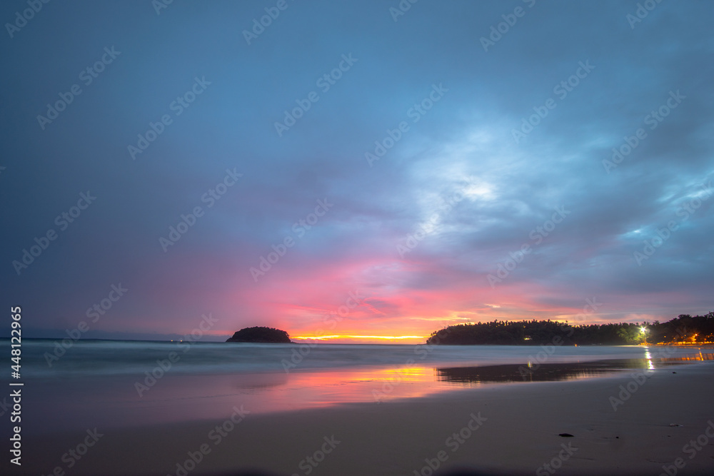 Obraz premium beautiful sunset behind Pu island at Kata beach Phuket. a lot of tourists relax on the beach during sunset..