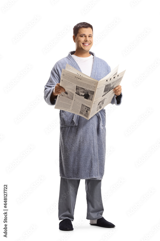 Man in pyjamas  and bathrobe standing and holding a newspaper
