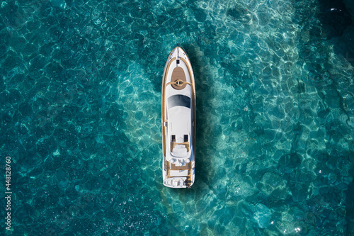 A huge white super Mega yacht on blue water in Italy. White sport yacht near the coast on the sea aerial view. Superyacht on clear water near the rocks, top view.