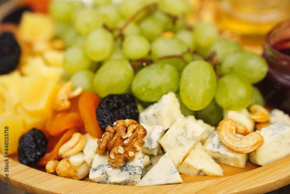 selective focus. cheeses, grapes, dried fruits, nuts, honey and jam