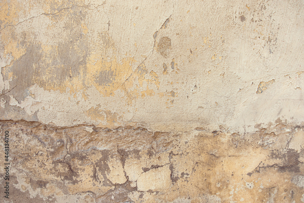 Old cracked weathered painted wall background texture. Dirty peeled plaster wall with falling off flakes of paint