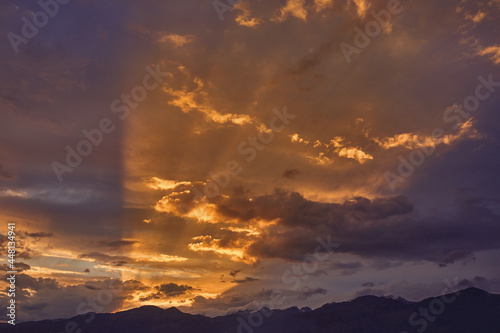 Mountain landscape at sunset. Sun's rays break through the beautiful cumulus clouds. Romantic atmosphere.