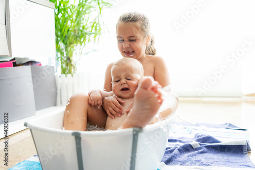 Caucasian boy and girl having fun in a bathtub in the middle of the living room. Fun bath concept.