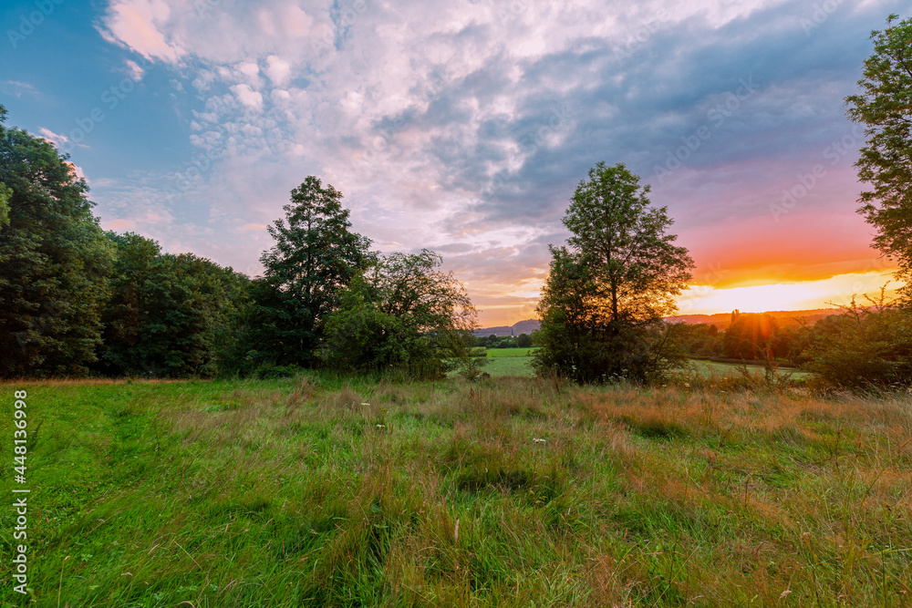 Colorful sunset on a warm summer evening over the rolling hills in Limburg. The sky showed amazing colours which gives a natural contrast to the green colours of the forest and meadow Colorful sunset on a warm summer evening over the rolling hills in Limburg. The sky showed amazing colours which gives a natural contrast to the green colours of the forest and meadow
