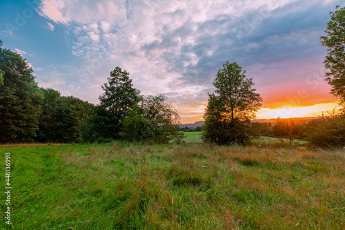 Colorful sunset on a warm summer evening over the rolling hills in Limburg. The sky showed amazing colours which gives a natural contrast to the green colours of the forest and meadow
