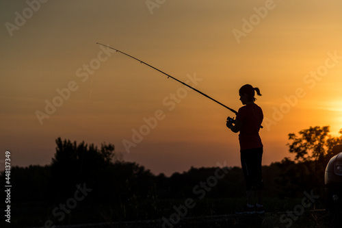 Silhouette of Woman Fishing at Sunset
