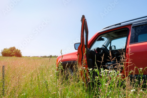 Red open car in the grass outdoors on a sunny day. Travel concept