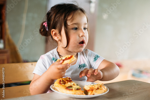 A girl, a child on the street eats a mini pizza very appetizing
