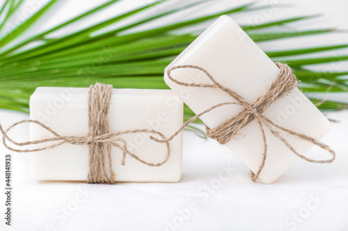 cosmetic flat lay: white soap on a white background with a green sprig 